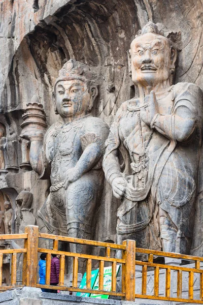 Visitantes cerca de esculturas budistas en gruta —  Fotos de Stock