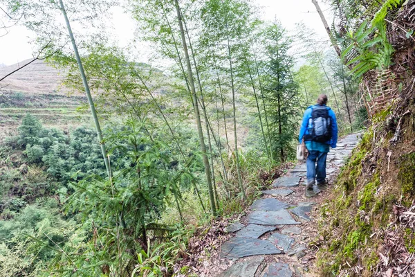 Tourist walk at wet path on slope of green hill — Stock Photo, Image