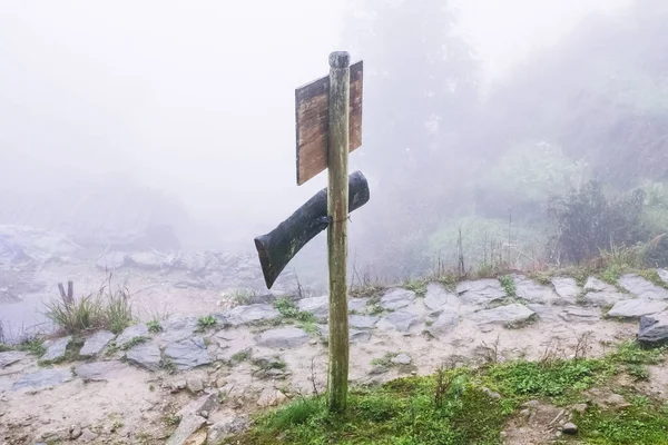 Direction sign on mountain path in misty day — Stock Photo, Image