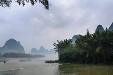 passenger boads in mist over river near Xingping clipart
