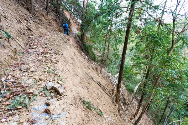 Tourist walks on path through mudslide on mountain — Stock Photo, Image