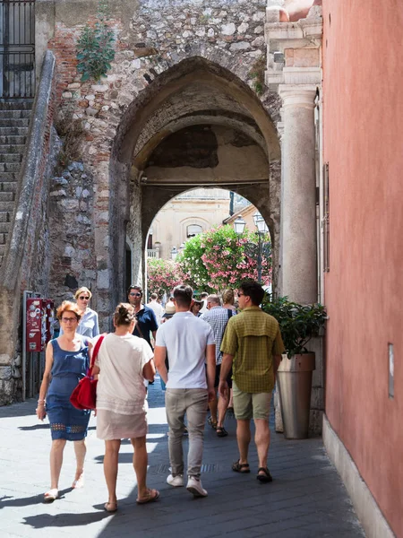 Personas caminan a través de puerta de entrada en la pared en Taormina — Foto de Stock