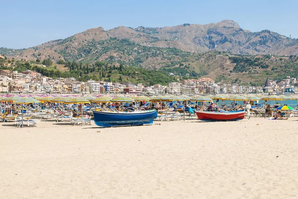 Semesterfirare och båtar på stranden i Giardini Naxos — Stockfoto