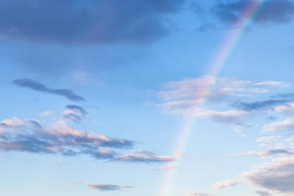 Rainbow and gray clouds in blue evening sky — Stock Photo, Image