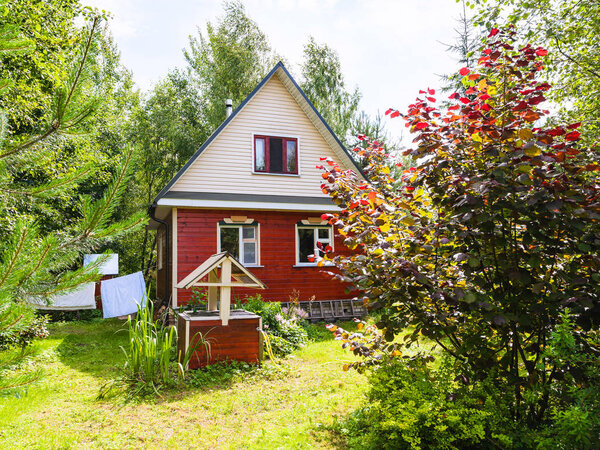 wooden cottage and well on backyard in village