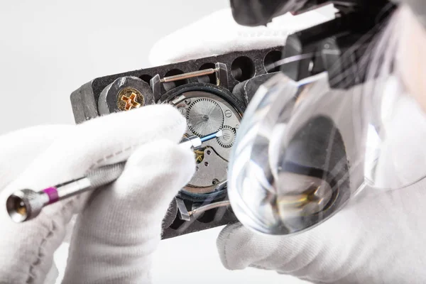 Watchmaker in head magnifier repairs wristwatch — Stock Photo, Image