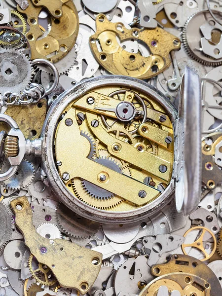 Open silver pocket watch on pile of spare parts — Stock Photo, Image