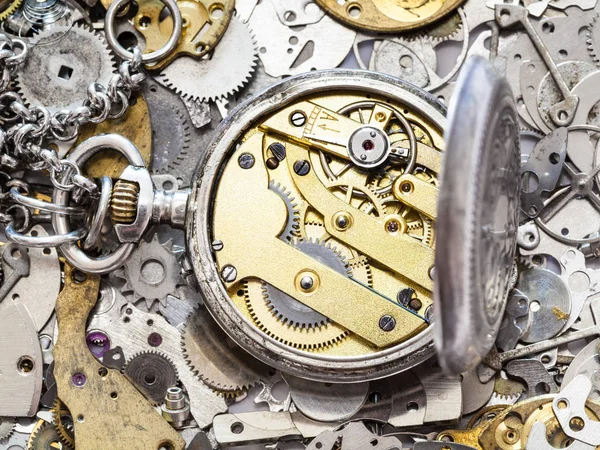 Open silver pocket watch on heap of spare parts — Stock Photo, Image