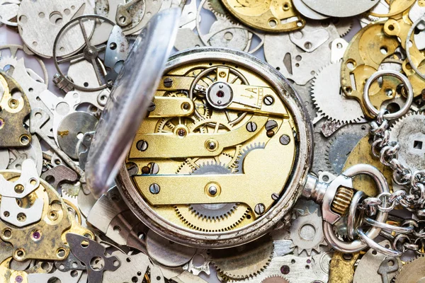 Open vintage pocket watch on heap of spare parts — Stock Photo, Image