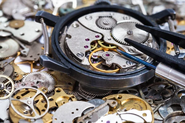 Tools on open watch on pile of clock spare parts — Stock Photo, Image