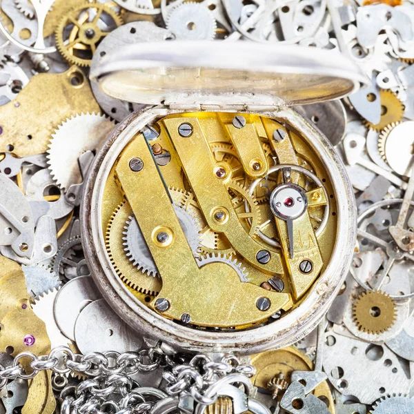 Open retro pocket watch on pile of spare parts — Stock Photo, Image