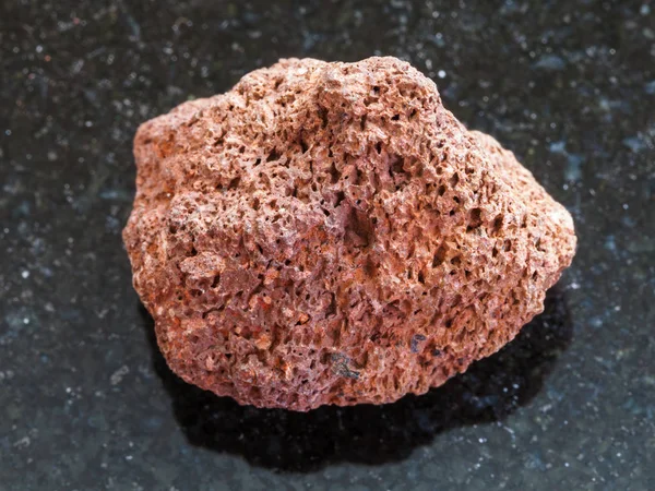 Tumbled red pumice stone on dark background — Stock Photo, Image