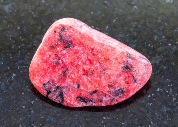 Piedra preciosa de ágata roja caída sobre fondo oscuro — Foto de Stock