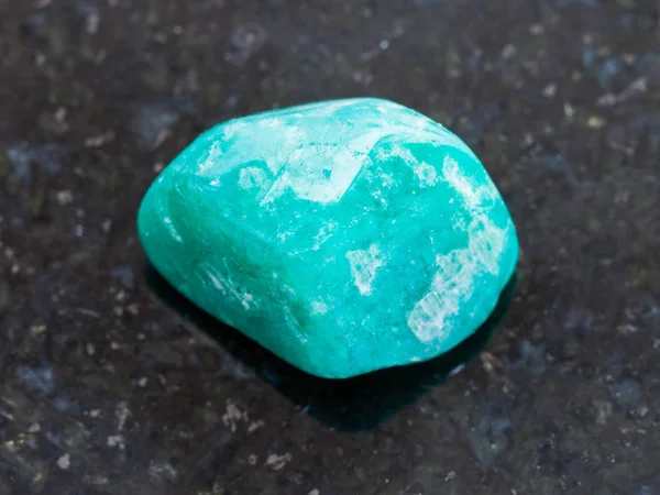 Tumbled amazonite gem on dark granite background — Stock Photo, Image