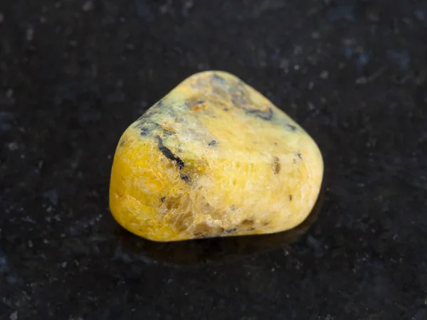 Piedra preciosa de ágata amarilla tumbada sobre fondo oscuro — Foto de Stock