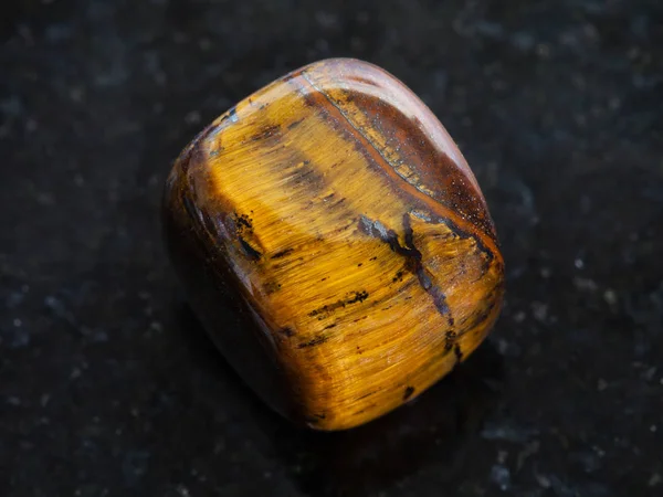 Piedra de gema de ojo de tigre pulido sobre fondo oscuro — Foto de Stock