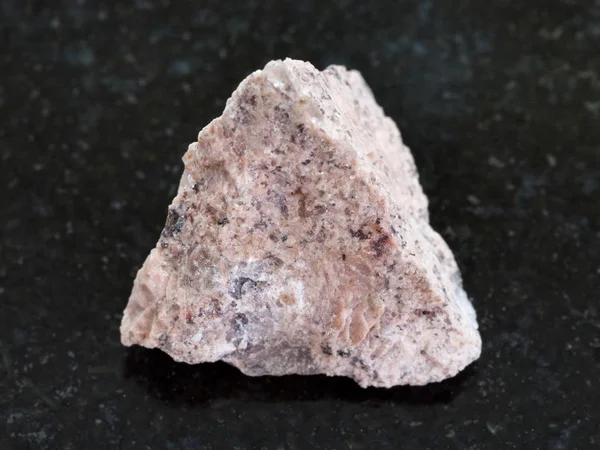 Piedra de granito en bruto sobre fondo de granito oscuro — Foto de Stock