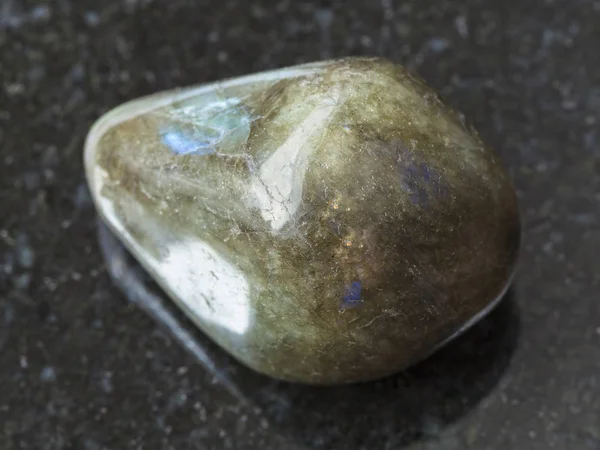 Piedra de gema de labradorita tumbada sobre fondo oscuro — Foto de Stock