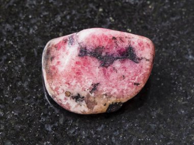 polished pink rhodonite gem stone on dark clipart