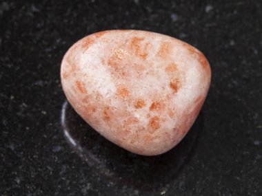 tumbled sunstone (heliolite) gem stone on dark clipart