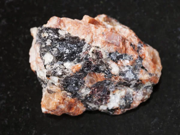 Raw red granite stone on dark background — Stock Photo, Image