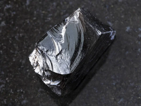 Trozo de Obsidiana cruda (vidrio volcánico) en la oscuridad — Foto de Stock