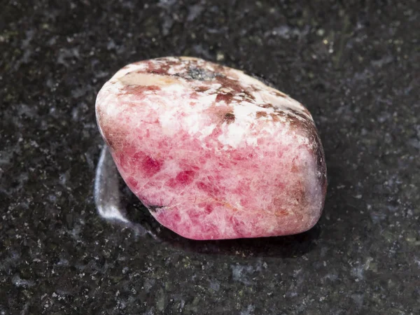Tuimelde roze Rhodoniet gem steen op donker — Stockfoto