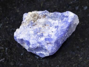 rough crystal of Tanzanite gemstone on dark clipart