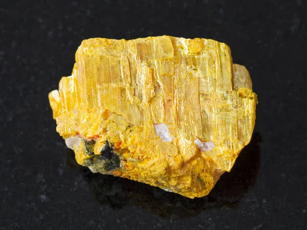 Raw native orpiment stone on dark background — Stock Photo, Image