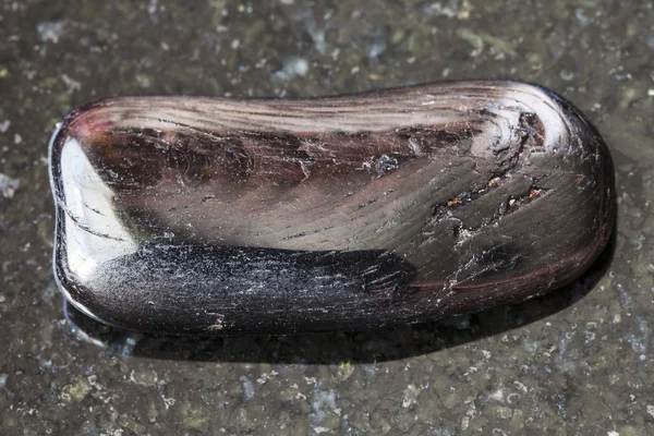 Getrommelter Hypersthene-Edelstein auf dunklem Hintergrund — Stockfoto