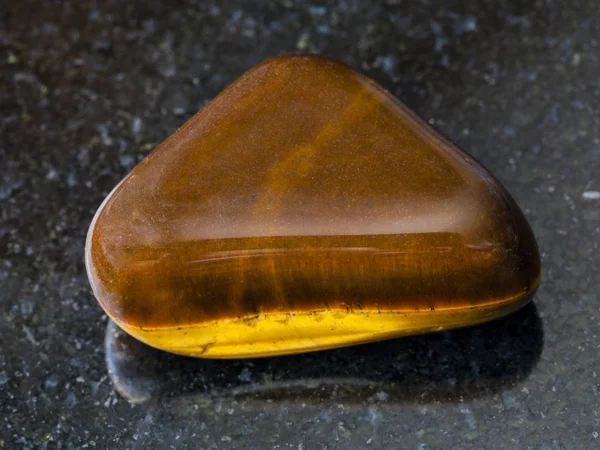 Tumbled tiger-eye gem stone on dark background — Stock Photo, Image