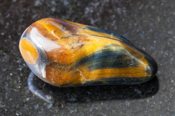 Tuimelde tiger-eye en hawk-eye edelsteen op donker — Stockfoto