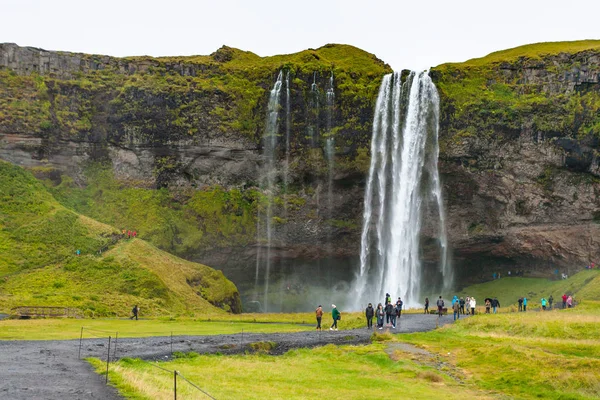 Turisták közelében Izland Seljalandsfoss-vízesés — Stock Fotó