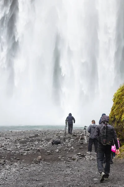 Turystów w dół wodospadu Skogafoss — Zdjęcie stockowe