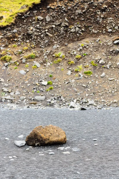 Roca en la playa de Reynisfjara cerca de la pendiente del monte — Foto de Stock