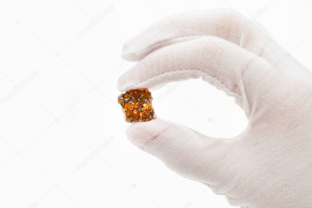 fingers in white glove holds spessartine crystals