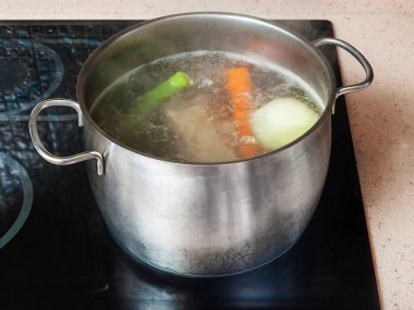 simmering meat stock in stockpot on ceramic cooker clipart