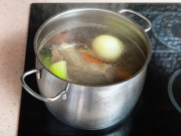 Cocción a fuego lento de caldo de carne en olla en cocina de cerámica — Foto de Stock