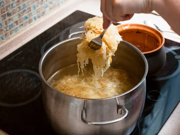 Masak bergerak sauerkraut dari pot ke saus — Stok Foto