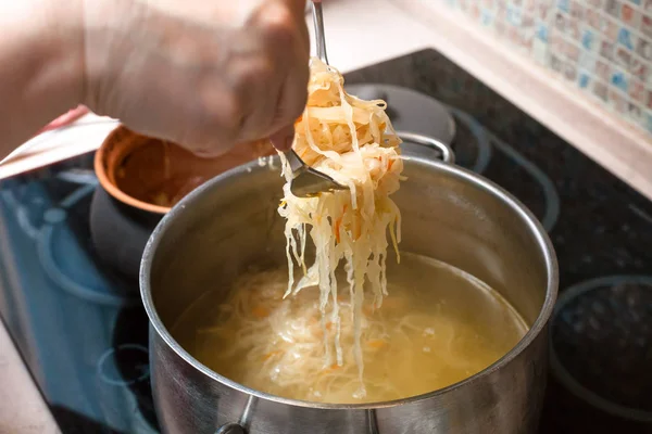 The cook transfer sauerkraut from pot in saucepan — Stock Photo, Image