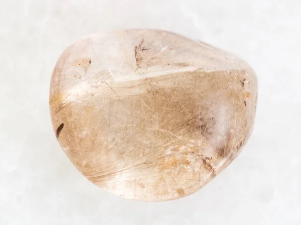 Polished Rutilated Quartz gemstone on white marble — Stock Photo, Image