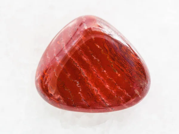 Polierter Edelstein aus rotem Jaspis auf weißem Marmor — Stockfoto