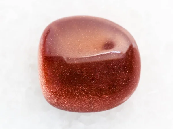 Polierter roter Goldstein Edelstein auf weißem Marmor — Stockfoto