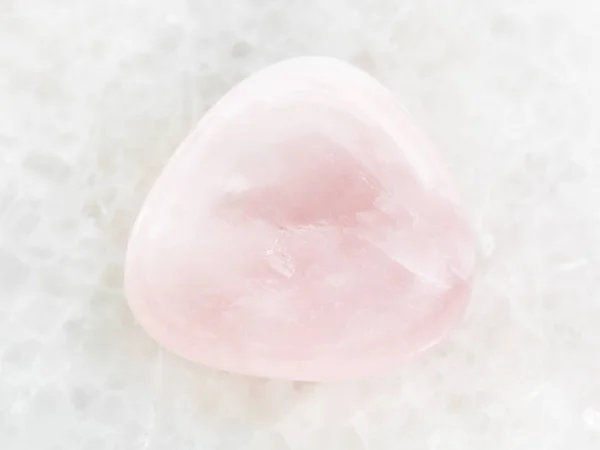 Piedra de gema de cuarzo rosa pulido sobre mármol blanco — Foto de Stock