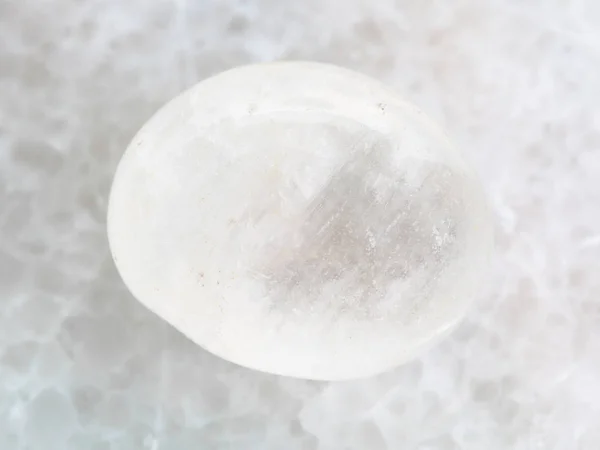 Trommelstein aus weißem Achat auf weißem Marmor — Stockfoto