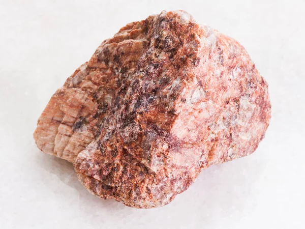 Ruwe roze granieten steen op wit marmer — Stockfoto