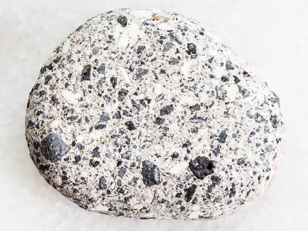 Pebble of gray Arkose sandstone on white marble — Stock Photo, Image