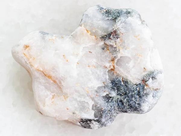 Pebble of rough marble stone on white marble — Stock Photo, Image