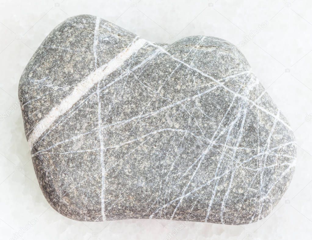 pebble of Greywacke sandstone on white marble
