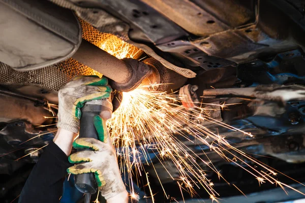 Repairer cuts old silencer on car by angle grinder — Stock Photo, Image